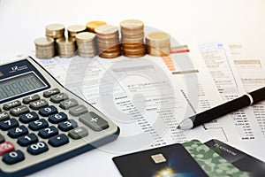 Close up of a credit cards with credit card statements, pen, stack of coins and calculator on white background, financial concept