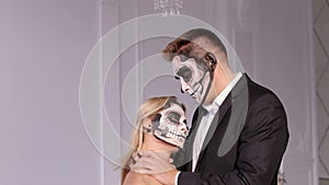 Close-up of a creepy girl with makeup for Halloween, a man holding her neck.