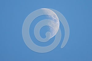 Close up of the crescent moon in the daytime with blue sky