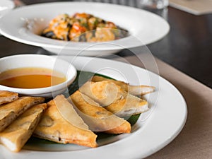 Close up of crispy spring roll stuffed with prawns and pork on a white plate in a restaurant