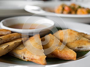 Close up of crispy spring roll stuffed with prawns and pork on a white plate in a restaurant