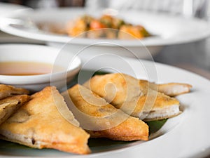 Close up of crispy spring roll stuffed with prawns and pork on a white plate in a restaurant