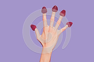 Close-up croopped delicate well-groomed hand five fingers sweet berries hats on nails isolated over pink pastel