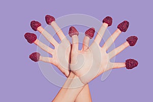 Close-up cropped delicate well-groomed two crossed hands ten fingers sweet berries hats on nails like wings isolated