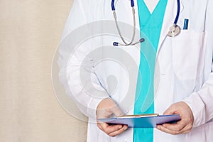 Close-up, cropped doctor with stethoscope and tablet for records. A man in a medical coat.