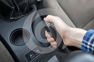 a close up cropped hand using the handbrake, driver sitting inside the car