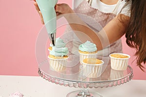 Close up cropped housewife female chef cook confectioner or baker in apron white t-shirt decorating cake cupcake at