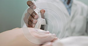 Close up cropped image of hand of male African doctor obstetrician sonographer with transducer, making ultrasound scan