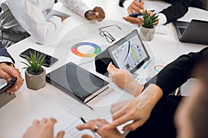 Close up cropped image of hands of diverse team of businesspeople, sitting at the table at office, and working with