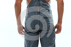 Close-up cropped image of male body, buttocks. Man in jeans posing isolated on white studio background.