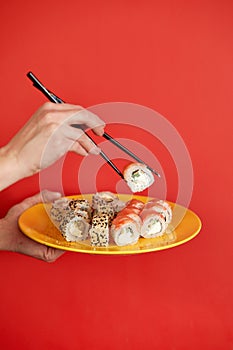 Close up cropped photo of female hand holds makizushi sushi roll served on plate traditional japanese food isolated on