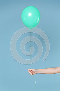 Close up cropped photo of female hold in hands turquoise azure air balloon isolated on blue wall background in studio