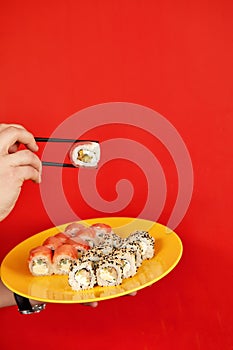 Close up cropped photo of male hold in hands makizushi sushi roll served on plate traditional japanese food isolated on