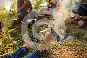 Close up cropped photo of man`s boots near the bonfire