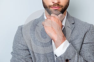Close up cropped photo of minded young man in formalwear touching his chin