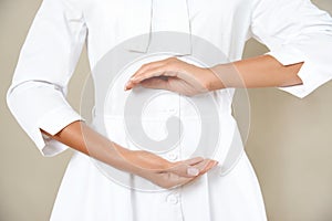 Close up cropped photo of woman`s slim stomach with her hands showing a balance in microflora in a white robe