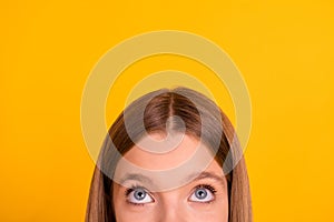 Close up cropped portrait of half face girl eyes look interested up empty space isolated on yellow color background