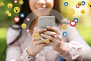 Close up cropped portrait of smiling young asian lady chatting at social networks on smartphone in park