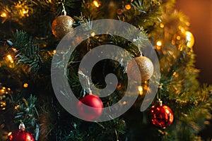 Close-up cropped shot of beautiful Christmas tree decorated with festive balls and celebration warm lights at home