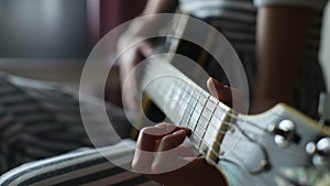 Close-up cropped shot of unrecognizable little girl learning to play guitar using electric guitar for music self