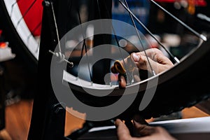 Close-up cropped shot of unrecognizable mechanic checking bicycle wheel spoke with bike spoke wrench working in bicycle