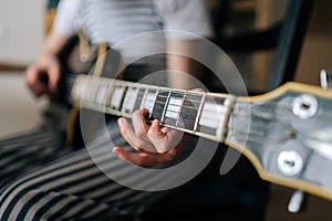 Close-up cropped shot of unrecognizable preteen girl learning to play guitar using electric guitar for music self