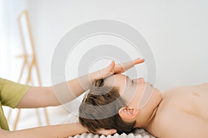 Close-up cropped shot of unrecognizable professional female physiotherapist doing neck adjustment to five year old boy