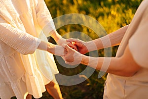 Close-up cropped shot of unrecognizable young couple in love standing on field in front of each other, holding hands