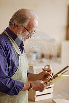 Close up cropped side view shot of grey haired grandpa making a drawing