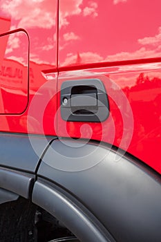 Close up cropped vertical photo of door handle on new red cabin truck