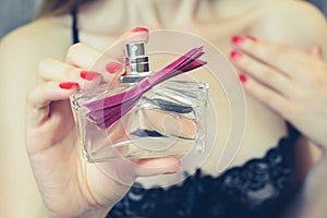 Close up cropped view photo. Woman in seductive clothes showing a bottle of perfume, seductive beautiful attractive sexual wo