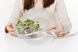 Close up cropped woman at table with green salad in glass bowl, tailor measuring tape isolated on white background