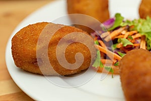 Close-up of a croquette with salad on a plate