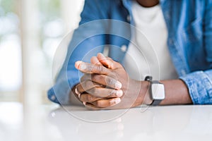 Close up of crossed hands of african man over table