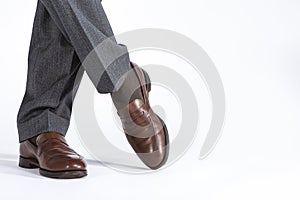 Close- up of Crossed Mens Legs Wearing Brown penny Loafers. Against White Background