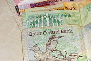 A close up of the  crrency of Qatar or  the Qatari Riyal notes of cash spread out on the white background. Money exchange