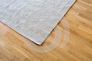 Close up of crumpled carpet laying on parquet wooden floor