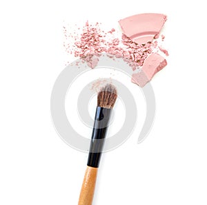 Close-up of crushed mineral shimmer powder golden color with makeup brush on white background.