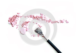 Close-up of crushed mineral shimmer powder golden color with makeup brush on white background.