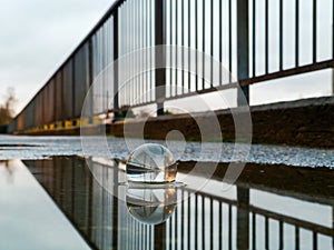 Close-up of a crystal ball in a puddle on a bridge