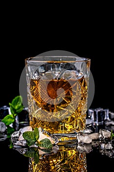 Close up of crystal glass of whiskey, brandy or scotch, ice and fresh mint on black background, Concept of delicious elite alcohol
