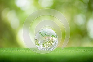 Close up of crystal globe resting on grass in a forest - environment concept. environmental, social, and governance in sustainable