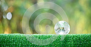 Close up of crystal globe resting on grass in a forest, world environment day or earth day concept. Sustainable protection of