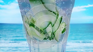 Close up of Cucumber drink cocktail with fresh water. It is home made cucumber limo. In the background is turquois water sea. It