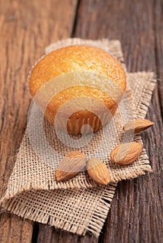 Close up a cup of almond cake against sack fabric on wooden table