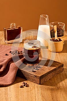 Close-up of a cup of black coffee displayed on a wooden platform with coffee beans and props on a wooden table with a brown