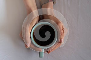 Close up of cup of coffee in bed.