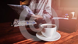 Close up cup  of coffee, Businessman reading news newspaper on desk in office . Newsletter concept