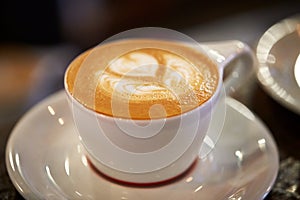 Close Up Of Cup Of Coffee With Design Poured Into Froth