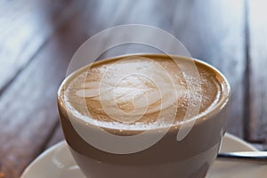Close up of a cup of coffee latte on wooden table in coffee shop